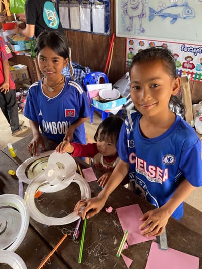 Leat Phary and a friend in football jerseys making paper crafts in their classroom