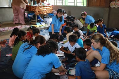Visiting students from Hong Kong doing art activities on the floor with children at Thon Pong Primary School