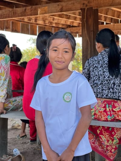 A teenage girl in a REEC t-shirt smiles at a community gathering