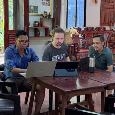Gergely Vajda and two REEC team members work together on laptops at a wooden table